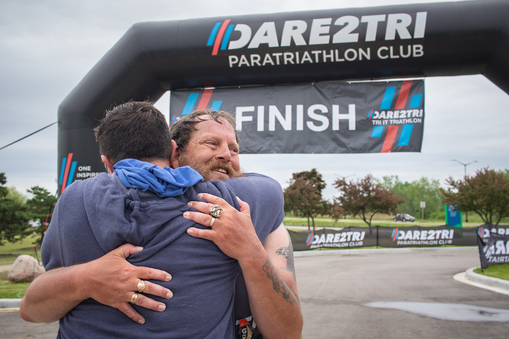 Dare2tri athlete Steve Johnson hugs prosthetist David Rotter at a triathlon finish line.