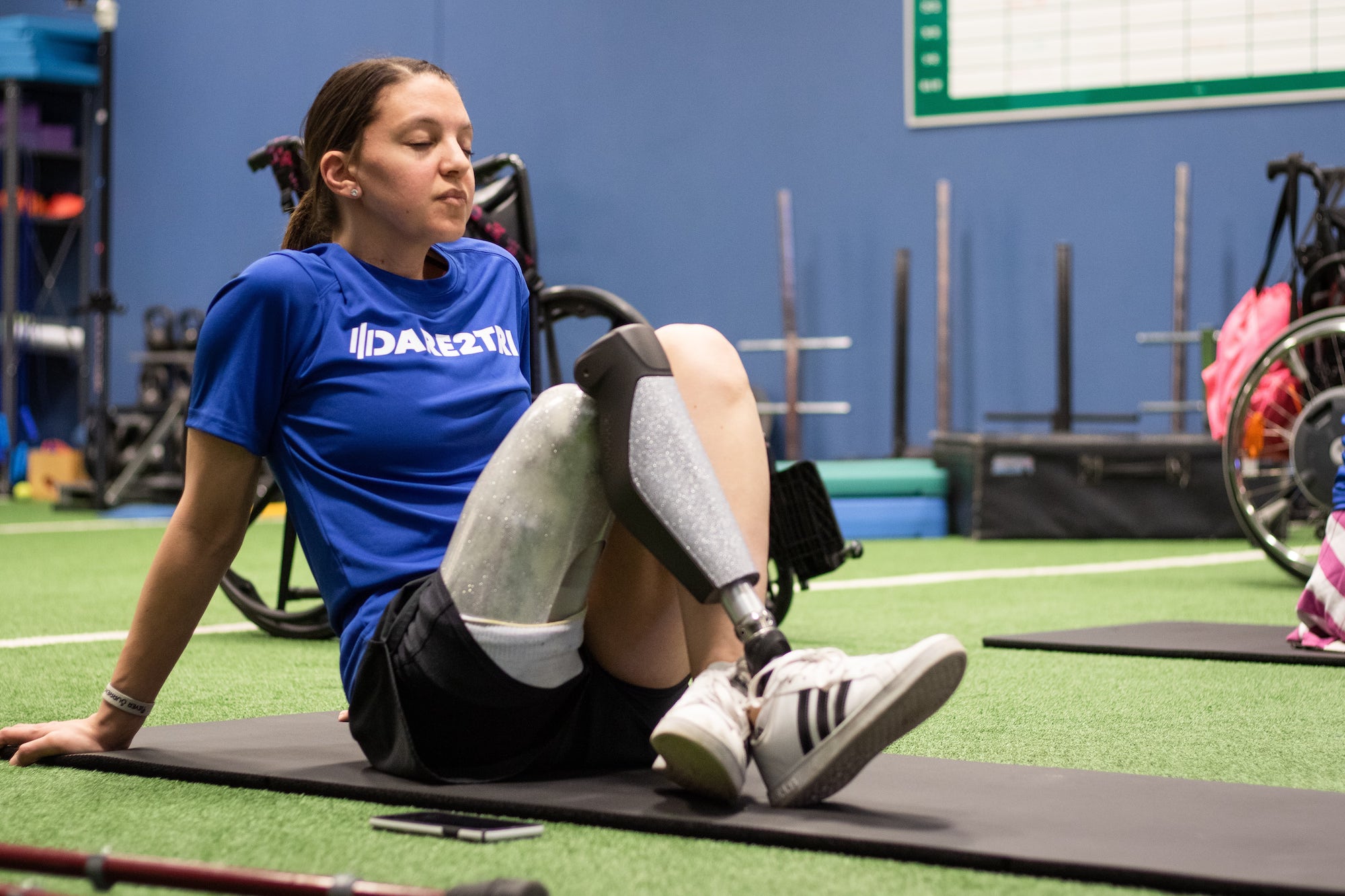 A Dare2tri athlete who has a leg amputation sits on a yoga mat.
